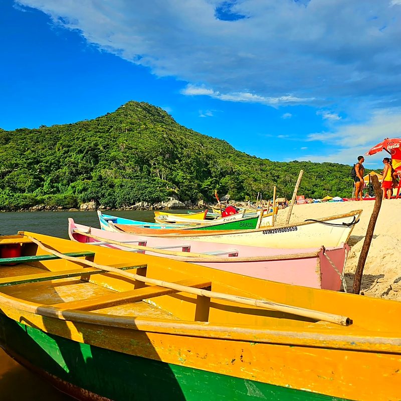 Proa de um barco de pesca colorido na Guarda do Embaú, com o morro ao fundo